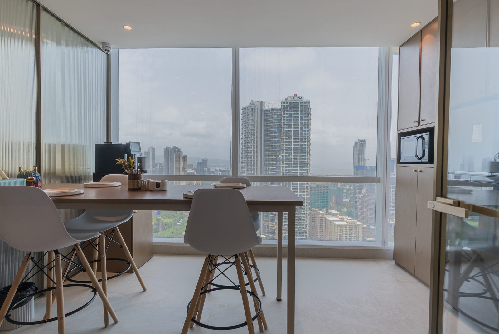 The pantry table against full height windows with the Mumbai skyline